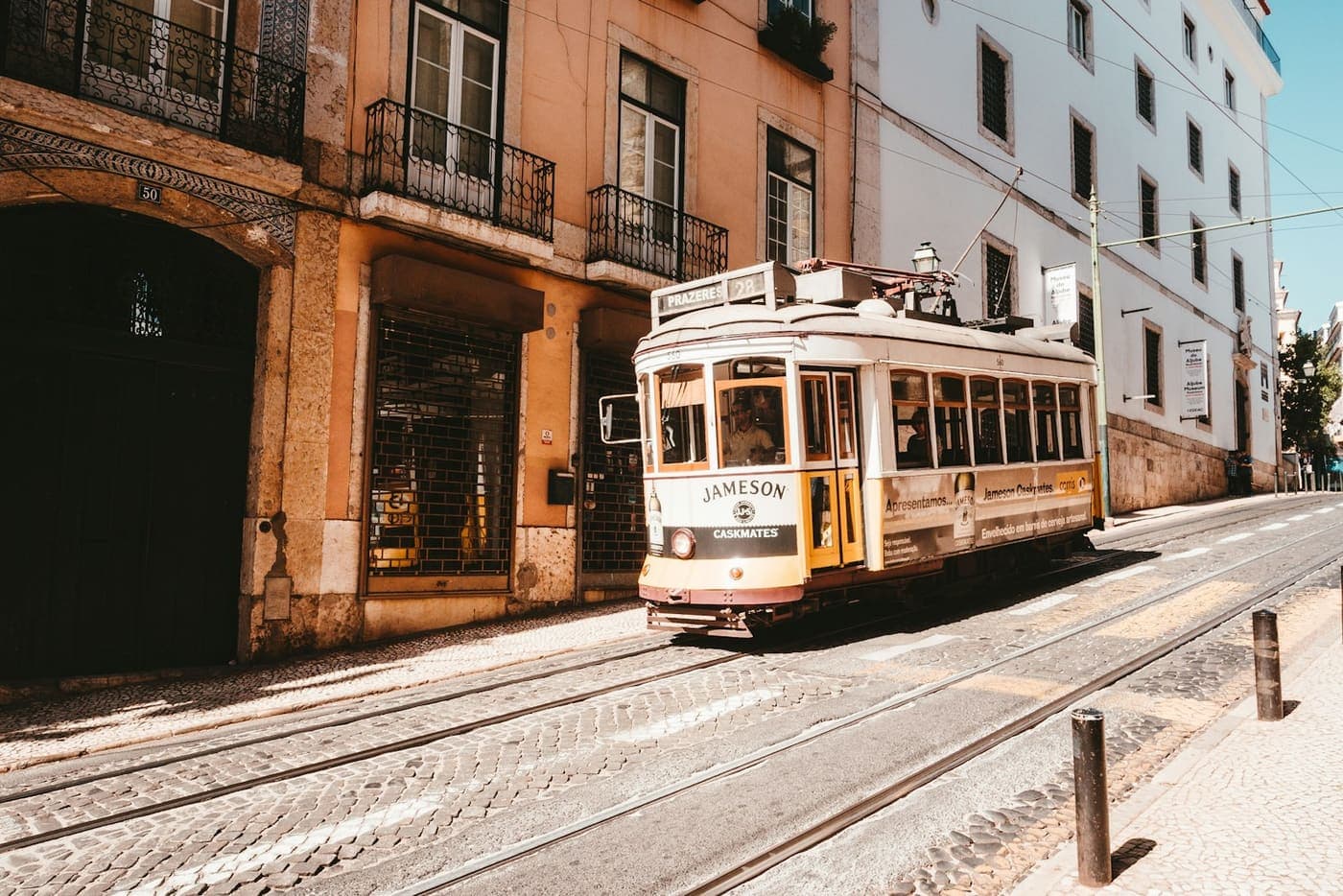 A yellow tram in a sunny Lisbon street